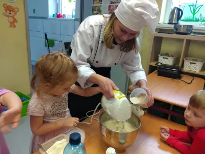 Pani w stroju kucharza robi ciasto z dziećmi