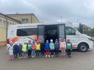 Grupa dzieci stojących przed autobusem